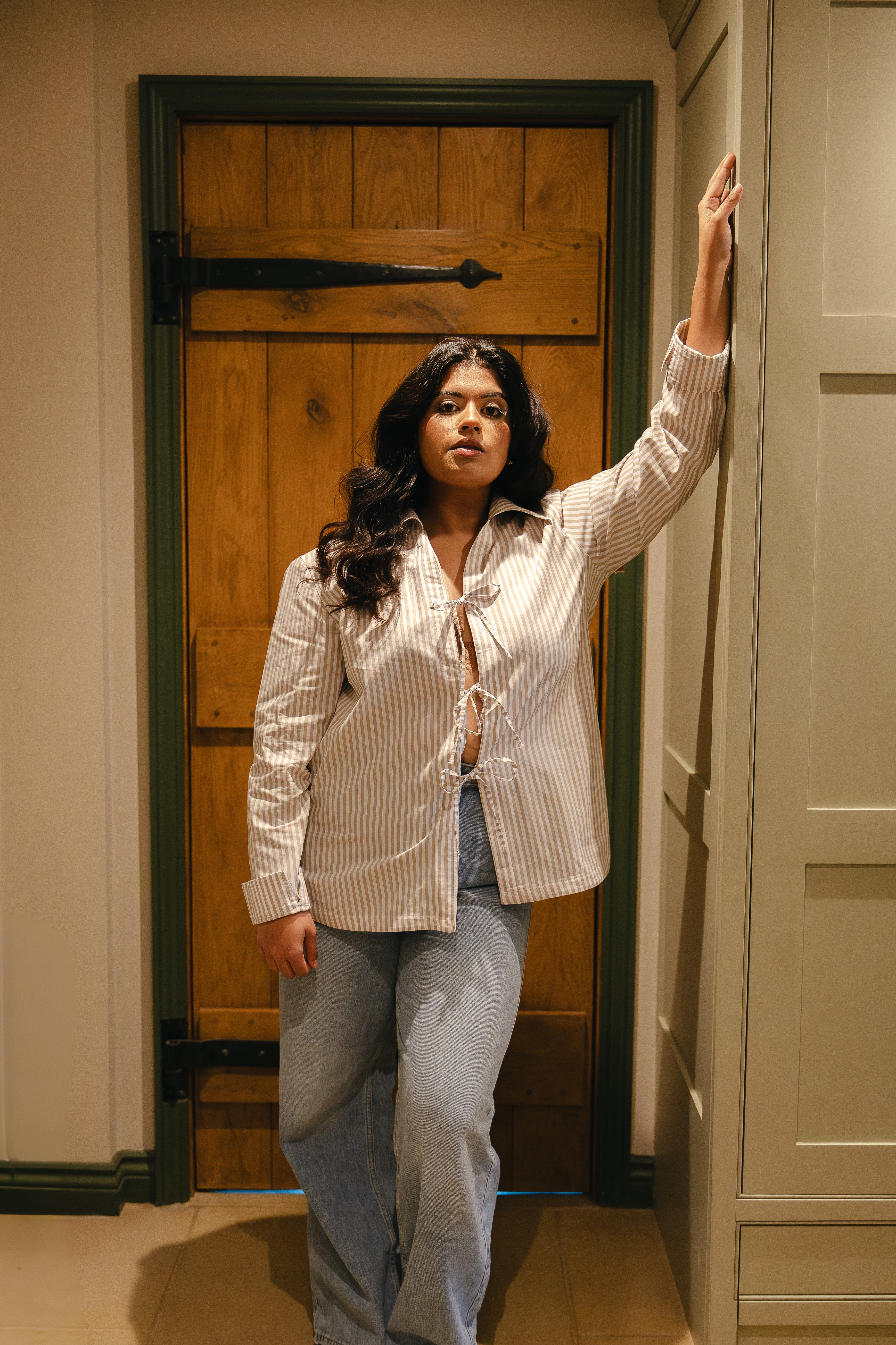 Model wearing pyjama neutral stripe long sleeve tie top and blue jeans